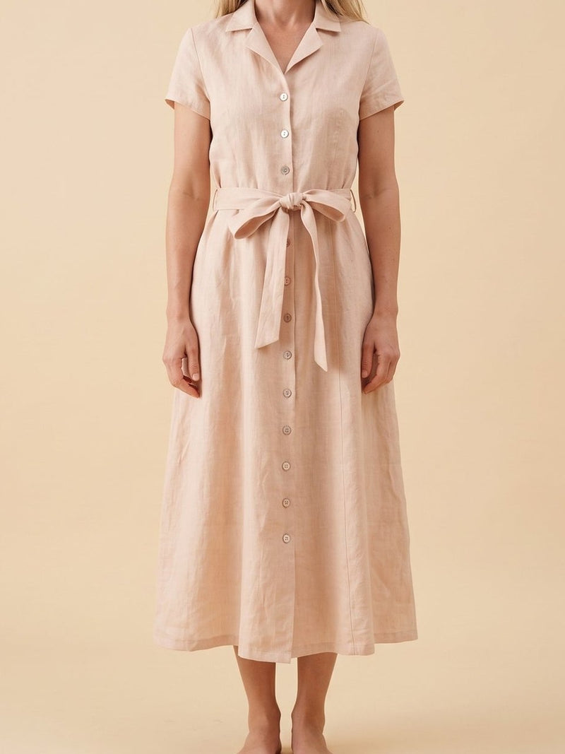 Blush pink linen shirt dress photographed in a lime-washed courtyard