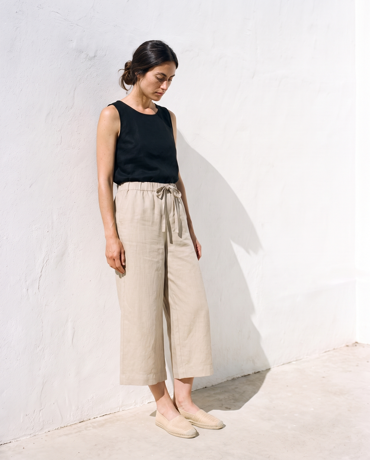 Carla Culottes in natural, leaning against a sunlit wall