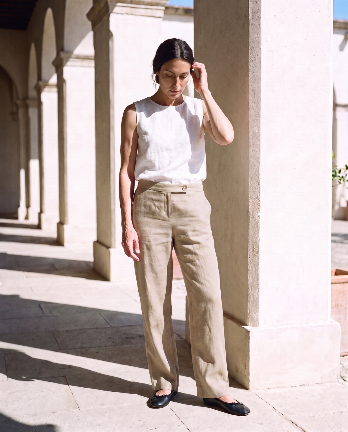 Nina Trousers in natural, weight shifted, tucking her hair behind her ear