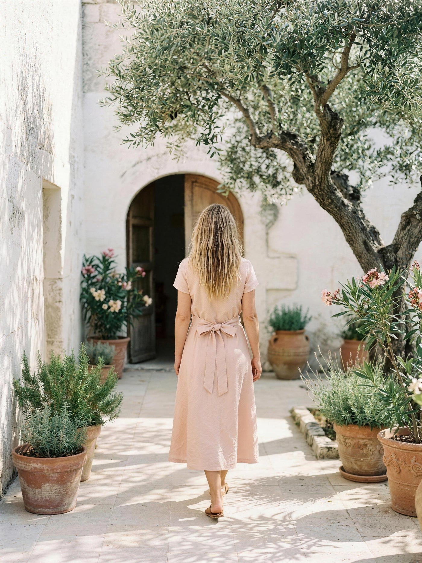 Blush pink linen shirt dress photographed in a lime-washed courtyard