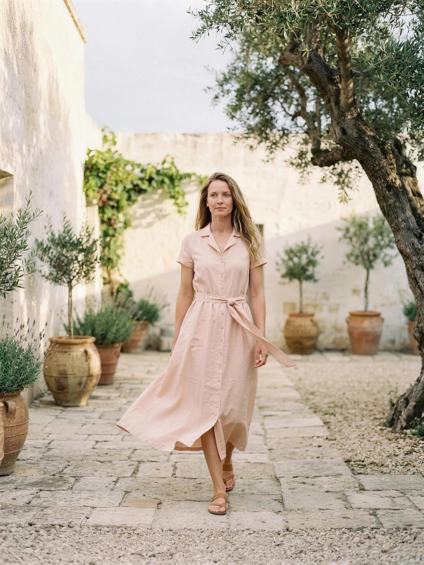 Blush pink linen shirt dress photographed in a lime-washed courtyard