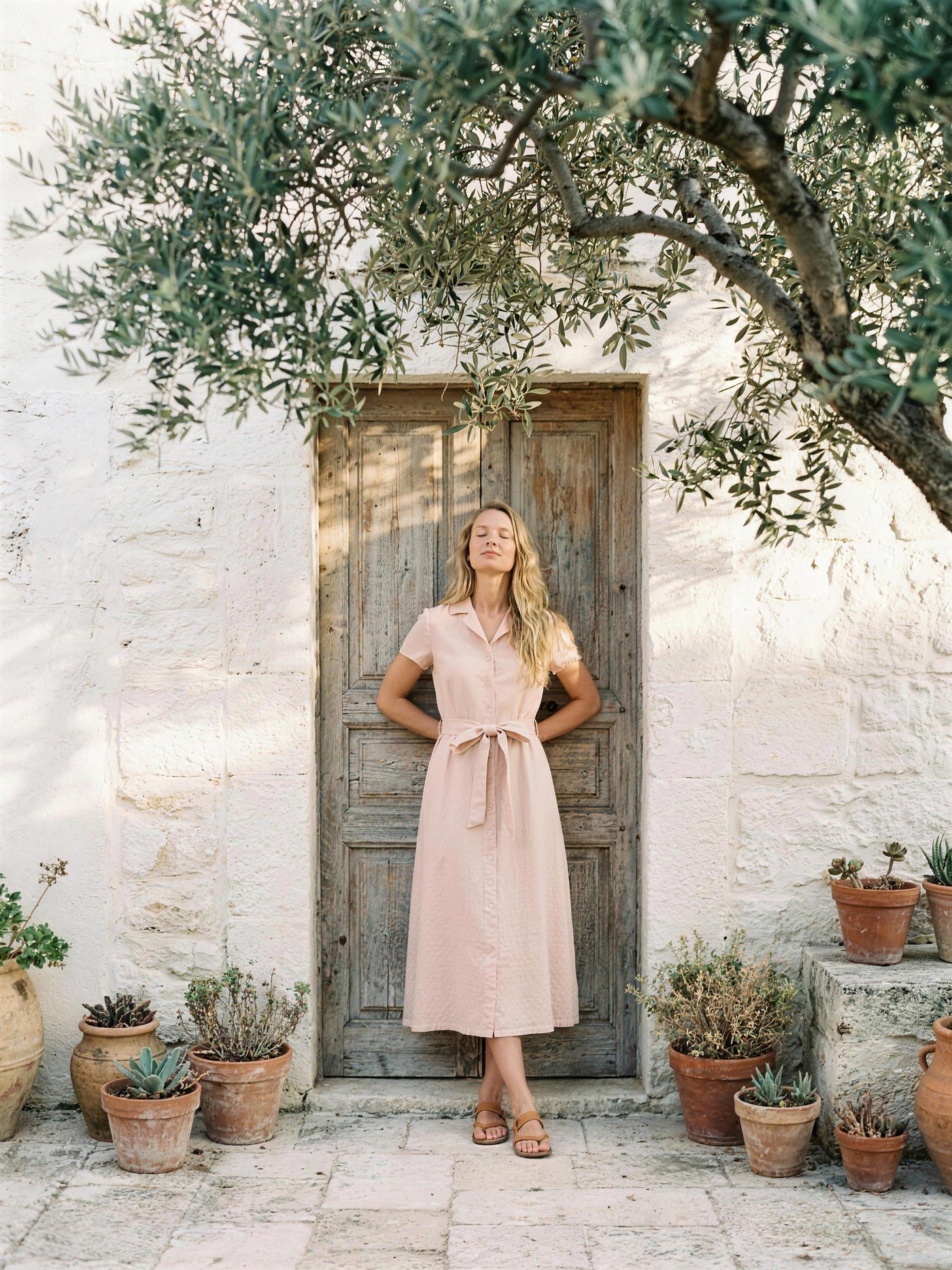 Blush pink linen shirt dress photographed in a lime-washed courtyard