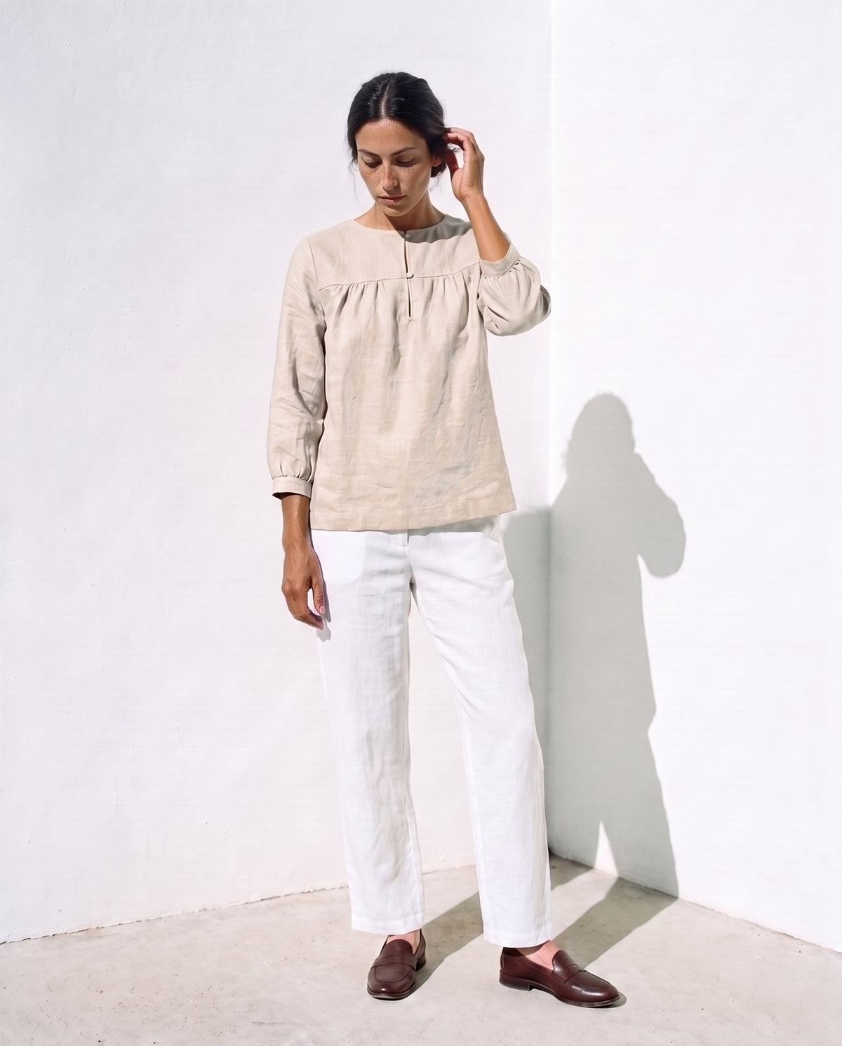 Ines Blouse in natural, weight shifted, tucking her hair behind her ear