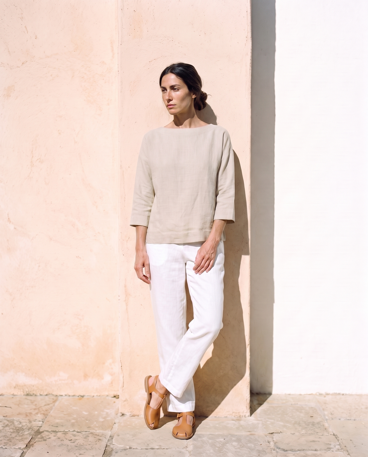Lia Top in natural, leaning against a sunlit wall